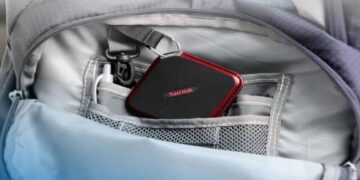 Pantalla bursátil mostrando el alza de las acciones de Sandisk en el Nasdaq junto a unidades de memoria SSD