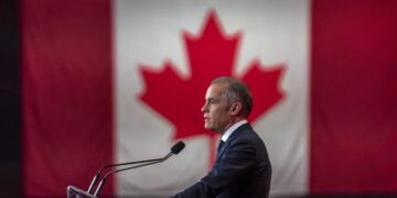 Banderas de Estados Unidos y Canadá frente a un puesto fronterizo comercial binacional