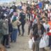 Personas migrantes en la playa de El Trampolín en Ceuta, con dispositivos de atención sanitaria al fondo