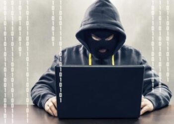 Persona revisando su tarjeta bancaria frente a una computadora tras detectar cargos no autorizados en República Dominicana