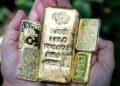 Lingotes de oro apilados sobre una superficie reflectante con el símbolo del dólar al fondo