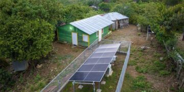 Técnicos instalando paneles solares fotovoltaicos en techos de viviendas rurales en las montañas de Pedro Santana, Elías Piña