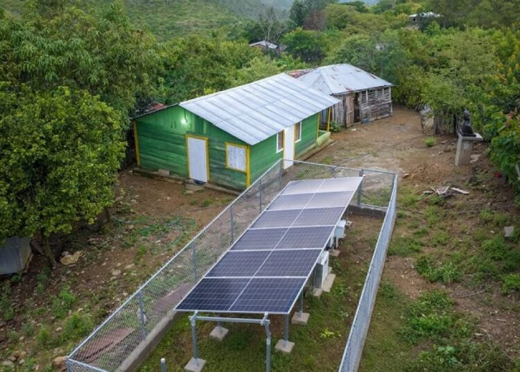 Técnicos instalando paneles solares fotovoltaicos en techos de viviendas rurales en las montañas de Pedro Santana, Elías Piña