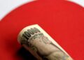 Billetes de yen japonés y dólares estadounidenses sobre una pantalla con cotizaciones cambiarias