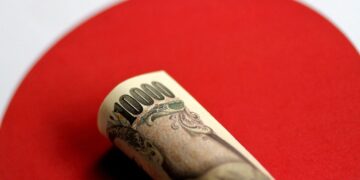 Billetes de yen japonés y dólares estadounidenses sobre una pantalla con cotizaciones cambiarias