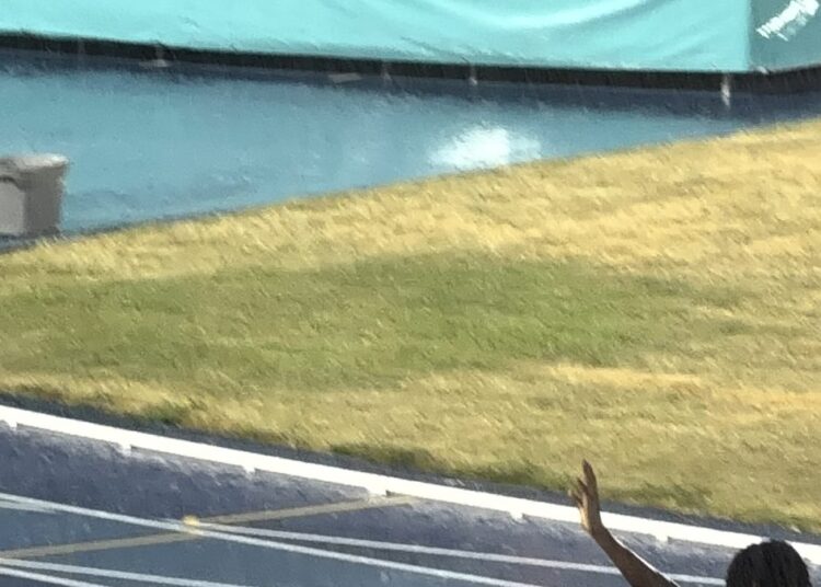 Marileidy Paulino envuelta en la bandera dominicana tras ganar el oro en los 400 metros de los Juegos CAC 2026 en el Estadio Olímpico Félix Sánchez