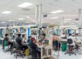 Trabajadores en planta industrial dominicana con maquinaria de producción en operación