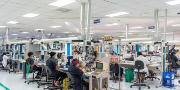Trabajadores en planta industrial dominicana con maquinaria de producción en operación