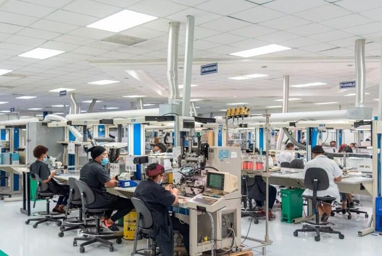 Trabajadores en planta industrial dominicana con maquinaria de producción en operación