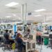 Trabajadores en planta industrial dominicana con maquinaria de producción en operación