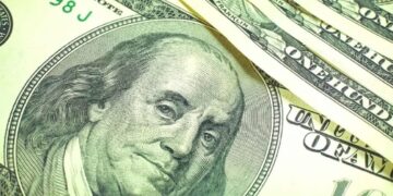 Billetes de peso mexicano y dólares estadounidenses sobre una mesa, reflejando la presión cambiaria del día