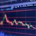 Pantalla de bolsa de valores mostrando caída del precio del petróleo Brent y alza de índices bursátiles globales