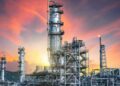 Plataforma petrolera en el mar con el Estrecho de Hormuz al fondo, reflejo de la tensión geopolítica que presiona los precios del crudo