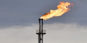 Buque petrolero navegando por el estrecho de Ormuz con instalaciones de extracción de crudo al fondo