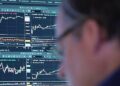 Instalación petrolera con barriles de crudo y precio del WTI en pantalla de mercados financieros