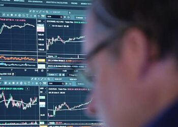 Instalación petrolera con barriles de crudo y precio del WTI en pantalla de mercados financieros