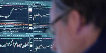 Instalación petrolera con barriles de crudo y precio del WTI en pantalla de mercados financieros