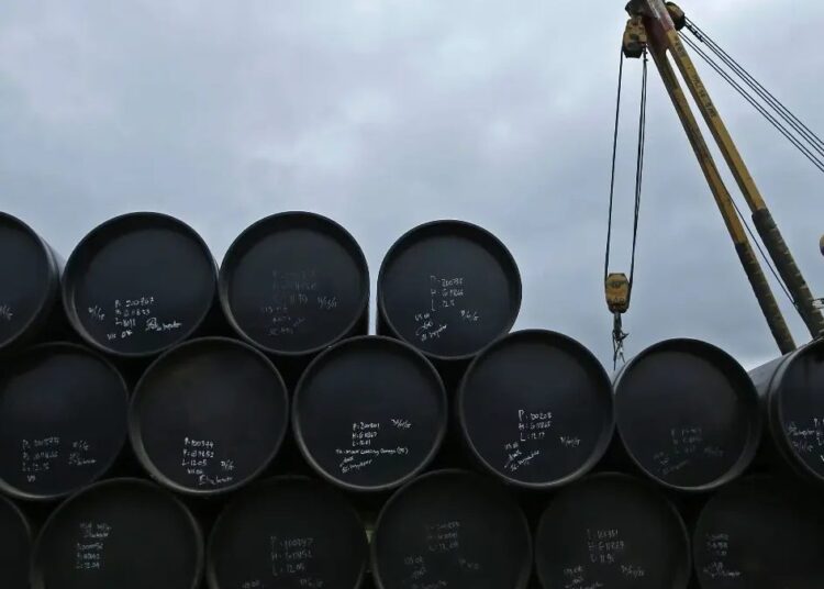 Buque petrolero navegando por el estrecho de Ormuz con plataformas de extracción de crudo al fondo