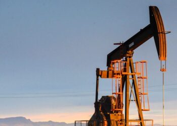 Plataforma petrolera con precio del WTI subiendo en pantalla de mercados ante tensión entre EE.UU. e Irán