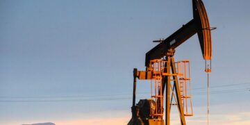 Plataforma petrolera con precio del WTI subiendo en pantalla de mercados ante tensión entre EE.UU. e Irán