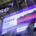 Barras de oro apiladas con cotización en pantalla financiera durante jornada de mercados en agosto de 2026