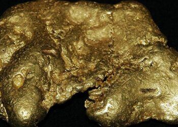 Lingotes de oro apilados sobre superficie metálica reflejando el alza del precio del oro en mercados internacionales