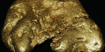 Lingotes de oro apilados sobre superficie metálica reflejando el alza del precio del oro en mercados internacionales