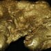 Lingotes de oro apilados sobre superficie metálica reflejando el alza del precio del oro en mercados internacionales