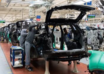 Línea de ensamblaje de vehículos en una planta automotriz de México con trabajadores y brazos robóticos