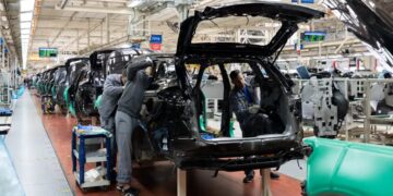 Línea de ensamblaje de vehículos en una planta automotriz de México con trabajadores y brazos robóticos