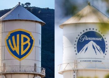 Logotipos de Warner Bros Discovery y Paramount Skydance en pantallas durante anuncio de fusión corporativa