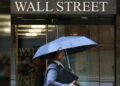 Pantalla electrónica en la Bolsa de Nueva York mostrando caídas del Dow Jones, S&P 500 y Nasdaq al cierre del viernes