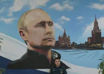 A serviceman of Russia's Emergencies Ministry sits under a mural depicting Russian President Vladimir Putin during Russia's parliamentary election at a polling station in Donetsk, Russian-controlled Ukraine, on September 20, 2026, amid the ongoing Russian-Ukrainian conflict. (Photo by AFP)