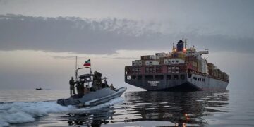Buque mercante navegando cerca del estrecho de Ormuz con tensión militar en la zona