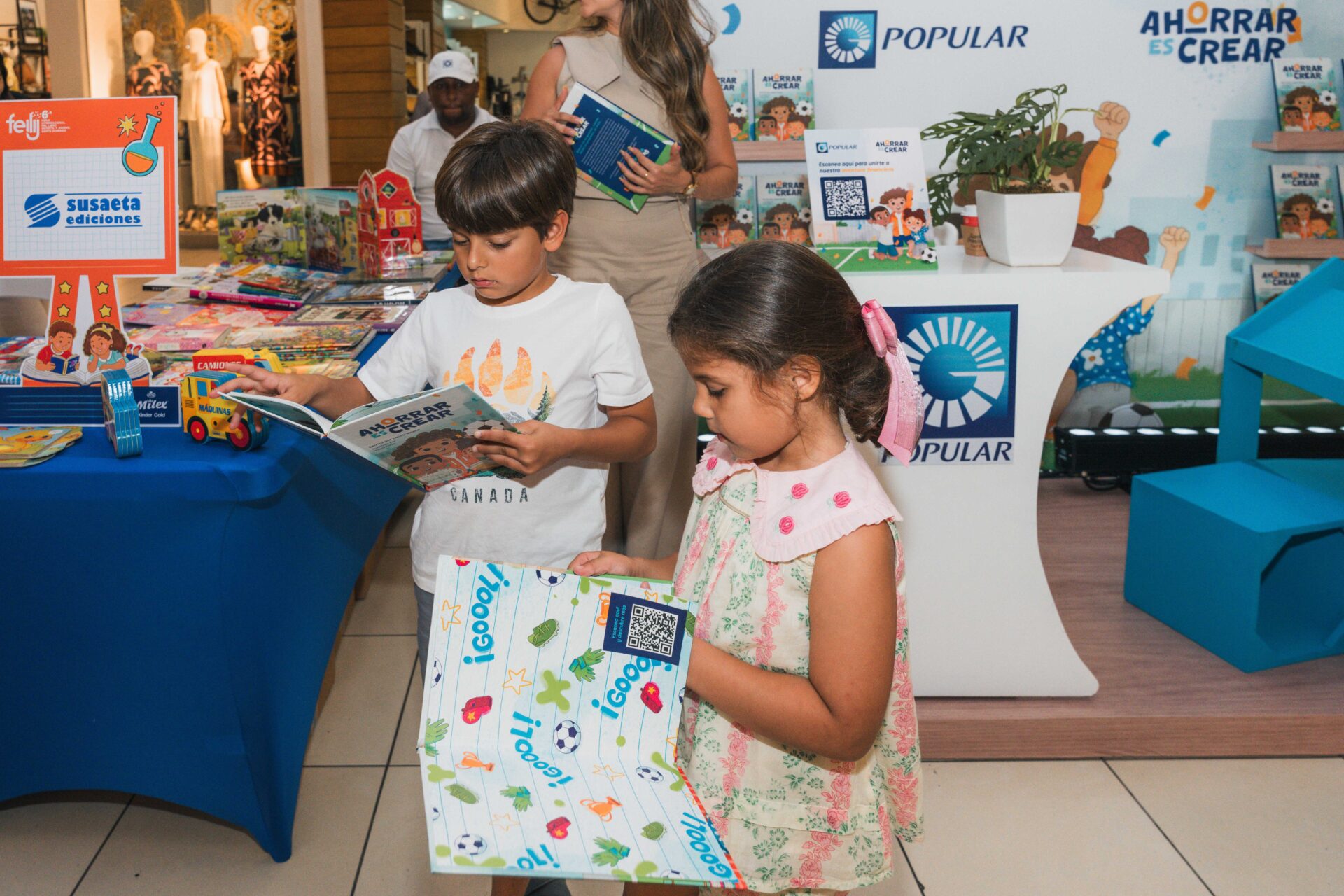 Dos niños hojean libros del programa Ahorrar es Crear del Banco Popular.
