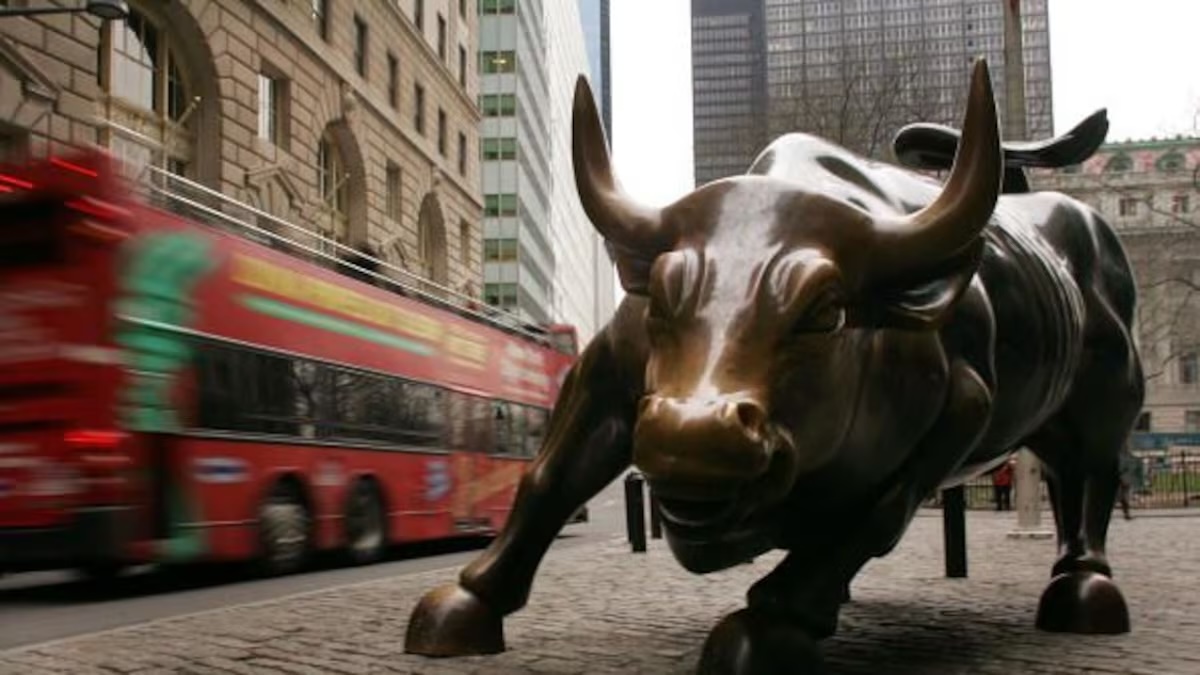 El Toro de Wall Street en el Bajo Manhattan con un autobús turístico rojo al fondo.