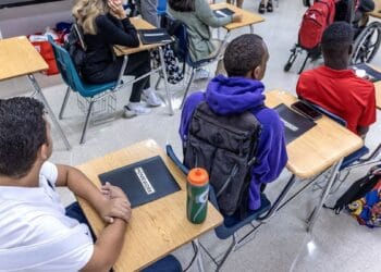 Estudiantes en un aula de Florida usando computadoras mientras un profesor supervisa la clase