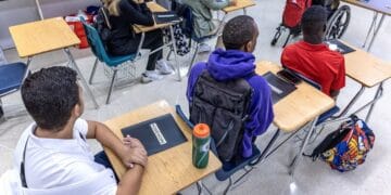 Estudiantes en un aula de Florida usando computadoras mientras un profesor supervisa la clase
