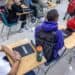Estudiantes en un aula de Florida usando computadoras mientras un profesor supervisa la clase