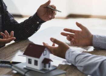 Hermanos reunidos frente a una casa heredada discutiendo sobre su venta o copropiedad