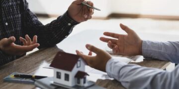Hermanos reunidos frente a una casa heredada discutiendo sobre su venta o copropiedad