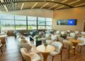 Interior del Lounge Popular en el Aeropuerto Internacional de Las Américas, con área de descanso y servicio de alimentos para tarjetahabientes