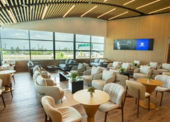 Interior del Lounge Popular en el Aeropuerto Internacional de Las Américas, con área de descanso y servicio de alimentos para tarjetahabientes