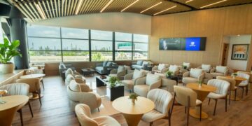 Interior del Lounge Popular en el Aeropuerto Internacional de Las Américas, con área de descanso y servicio de alimentos para tarjetahabientes