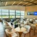 Interior del Lounge Popular en el Aeropuerto Internacional de Las Américas, con área de descanso y servicio de alimentos para tarjetahabientes