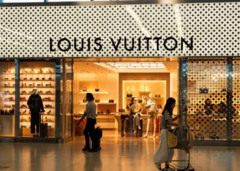 Fachada de tienda LVMH en avenida comercial de lujo con pasantes frente a escaparate