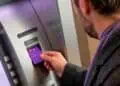 Tarjeta Nu morada sobre pantalla de cajero automático mostrando comisión de retiro de efectivo