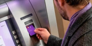Tarjeta Nu morada sobre pantalla de cajero automático mostrando comisión de retiro de efectivo