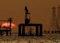 Instalaciones petroleras en Venezuela con trabajadores y equipos de extracción de crudo al atardecer