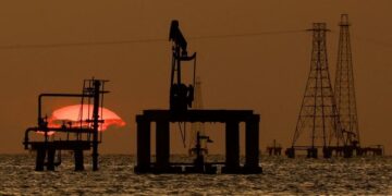 Instalaciones petroleras en Venezuela con trabajadores y equipos de extracción de crudo al atardecer